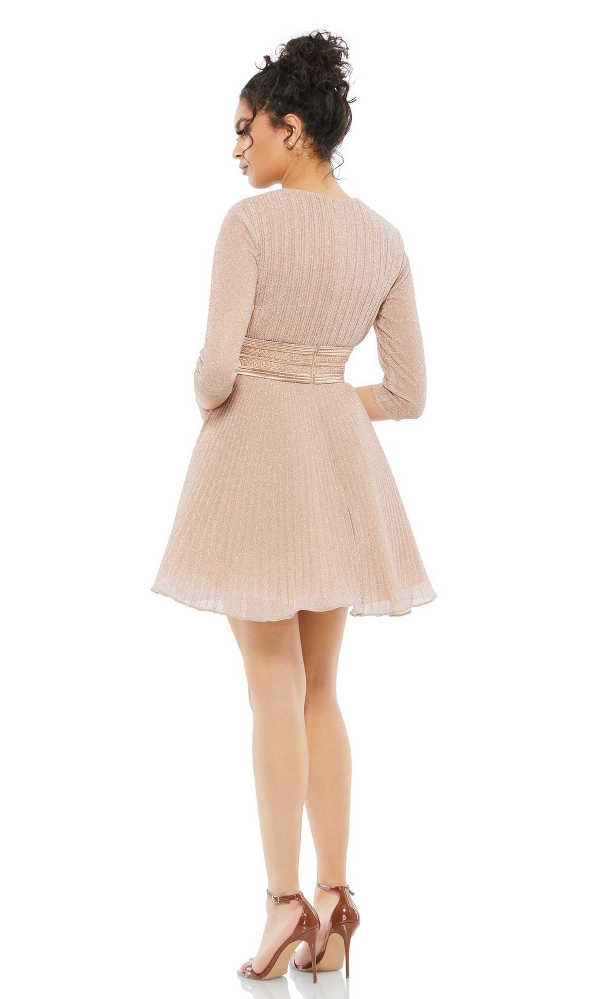 Woman facing away from the camera in the Short Party Dress 30749 by Mac Duggal, a light pink, pleated A-line party dress with long sleeves and a banded waist, styled with nude high-heeled sandals.